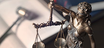 Justice with her scales, and a gavel and book in the background